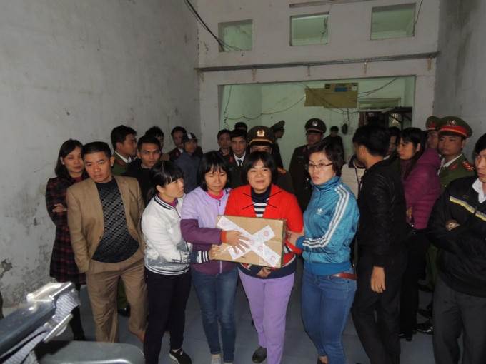 Cơ quan An ninh điều tra Công an tỉnh Hà Nam dẫn giải Trần Thị Nga (dấu X) và một số vật chứng liên quan.