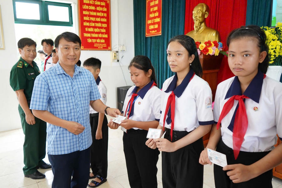 Ông Tăng Thiện Tính - Phó Chủ tịch UBND xã Đất Mũi tặng BHYT cho học sinh nghèo.