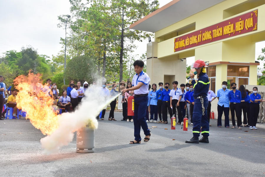Cán bộ phòng Cảnh sát PCCC và CNCH Công an Bạc Liêu hướng dẫn các em học sinh sử dụng bình chữa cháy xách tay để dập lửa.
