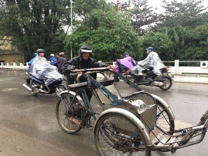 Nhiều người dù già nhưng vẫn tranh thủ chạy xích lô để kiếm thêm tiền ngày mưa, gió (Ảnh: Thân Hiền)