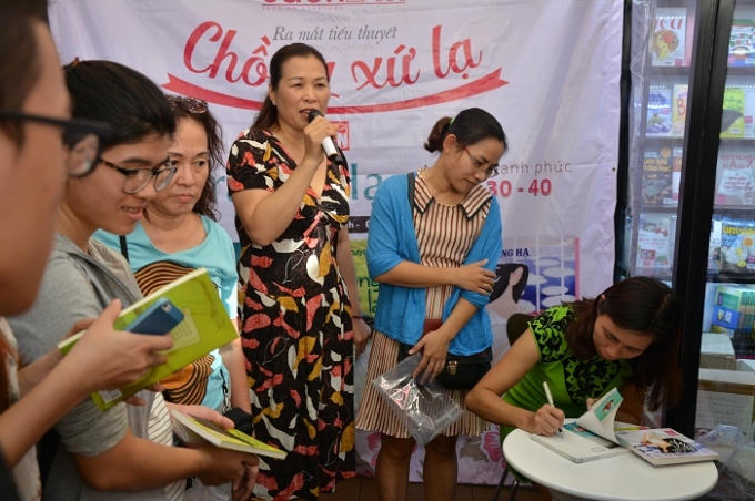 Nhà văn Trang Hạ ký tặng đọc giả cuốn sách tiểu thuyết Chồng xứ lạ của mình ra mắt hôm nay.