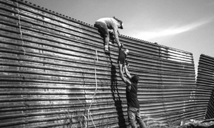 Một gia đình nhập cư trèo qua hàng rào ở biên giới Mỹ - Mexico hồi cuối tháng 11 năm ngoái.