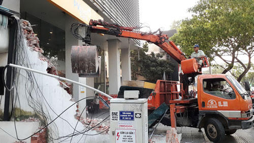 Lực lượng chức năng tháo dỡ bức tường cao 4 m trước Công ty Hoa tiêu hàng hải Khu vực 1 (đường Đinh Tiên Hoàng, phường Bến Nghé, quận 1, TP HCM) sáng 6-3 Ảnh: SỸ ĐÔNG
