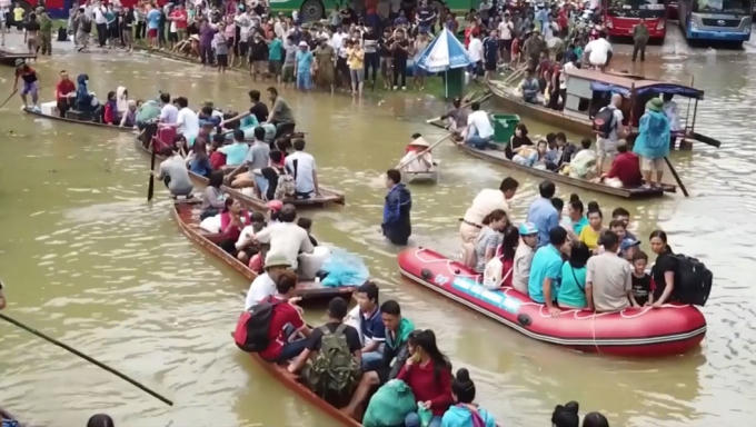 Lực lượng chức năng d&ugrave;ng thuyền để đưa người d&acirc;n qua khu vực ngập nước tr&ecirc;n quốc lộ 6.