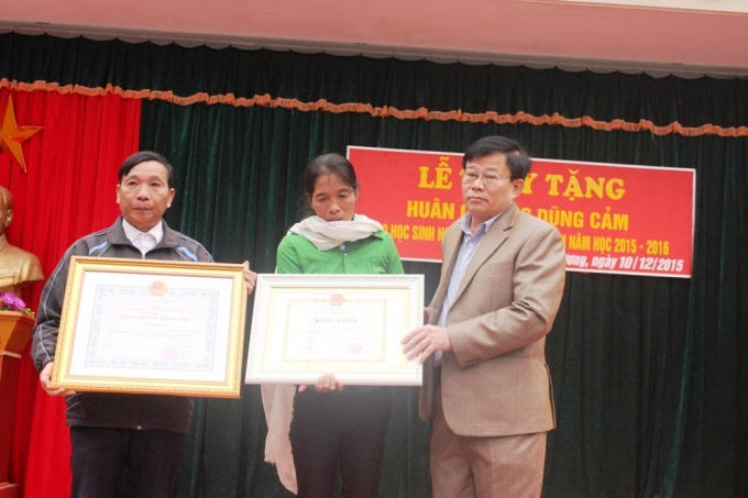 Ông Thái Huy Vinh - PGĐ Sở GD&amp;ĐT Nghệ An thừa ủy quyền của Chủ tịch nước trao tặng Huân chương Dũng cảm cho mẹ em Tuấn.