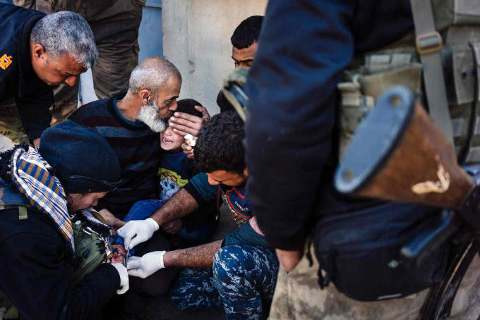 Một người Iraq cao tuổi an ủi một cậu bé bị thương và đang được điều trị bởi lực lượng y tế trong một khu phố tại "chiến trường" Mosul, Iraq. (Ảnh: AFP / Getty Images)