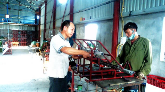 Anh Trần Đại Nghĩa đang hướng dẫn công nhân chỉnh sửa những khâu đoạn kỹ thuật của máy cấy.