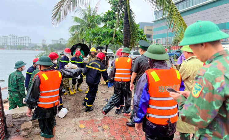 Các lực lượng cứu hộ đưa thi thể lên bờ. Ảnh QMG