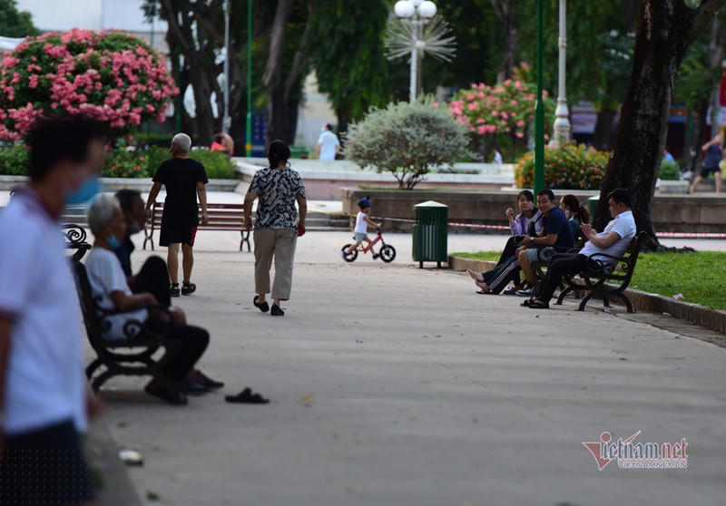 Trong ảnh, người đi bộ thể dục trong công viên bỏ khẩu trang, ngồi khá gần nhau