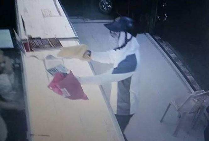 Tên cướp giơ vật gống khẩu súng được giấu trong chiếc túi màu vàng (Ảnh cắt từ video).