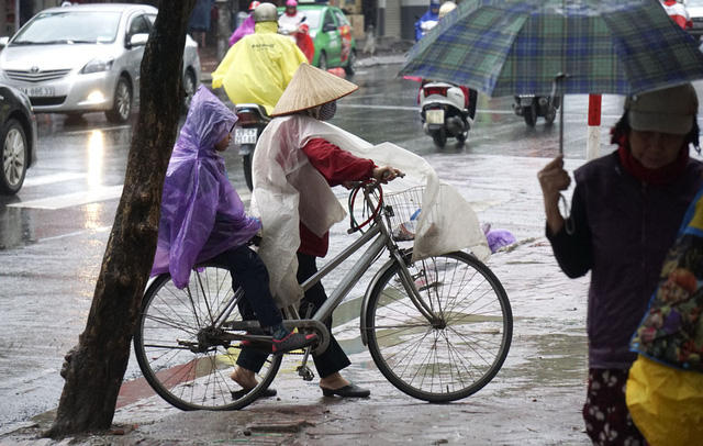 Không chỉ mưa, thời tiết cũng lạnh khiến các em nhỏ phải mặc áo mưa kín mít để đến trường.