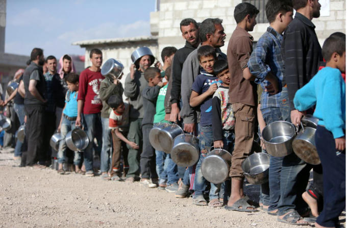 Người dân Syria đứng xếp hàng để nhận thức ăn được viện trợ. Ảnh: Reuters.