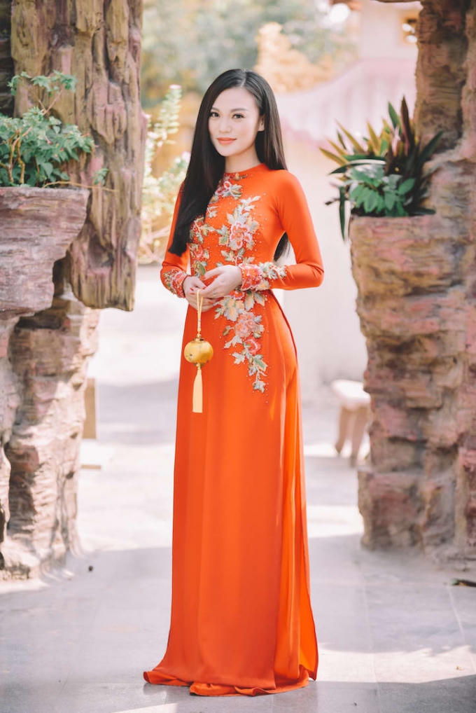 Cao Thùy Linh kiêu sa trong tà áo dài màu cam rực rỡ với nhiều họa tiết cầu kỳ ở phần ngực áo và tay áo