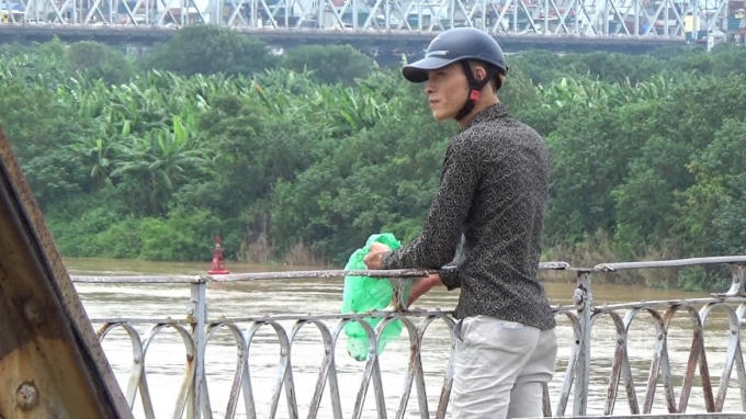 Người đàn ông này vô tư xả tro xuống sông Hồng. Ảnh: Chí Hiếu
