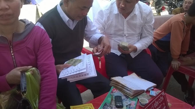 Một người đàn ông không có thẻ hành nghề của Ban quản lý di tích đền Cờn nhưng vẫn giải thẻ và vô tư nhận tiền lì xì rất hậu hĩnh từ du khách (ảnh Duy Ngợi).