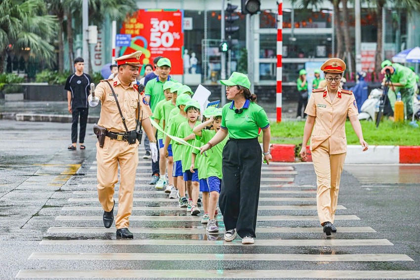 Cán bộ CSGT hướng dẫn học sinh cách sang đường đúng tín hiệu đèn và vạch kẻ đường.