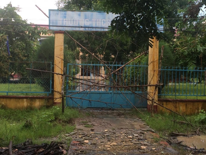 Cổng trường bị rào lại và dùng những cành cây khô chắn ngang.
