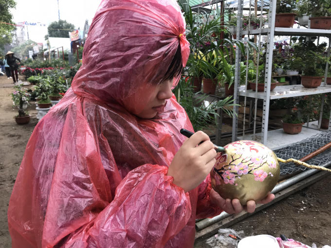 Một cô gái dầm mưa để trang trí cho quả dừa, tạo thành món hàng độc bán tết.