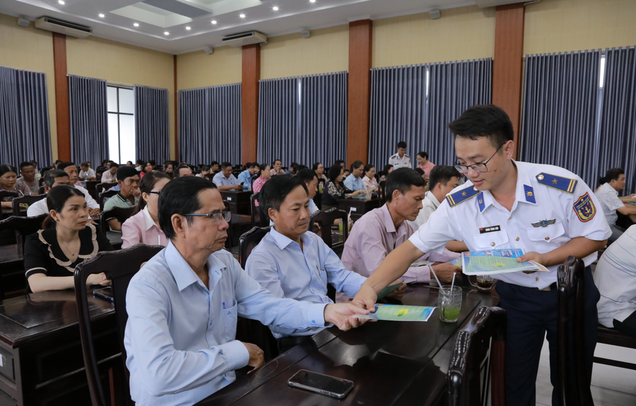 Cán bộ Bộ Tư lệnh Vùng Cảnh sát biển 4 phát tờ rơi tuyên truyền cho bà con ngư dân tham dự Hội nghị.