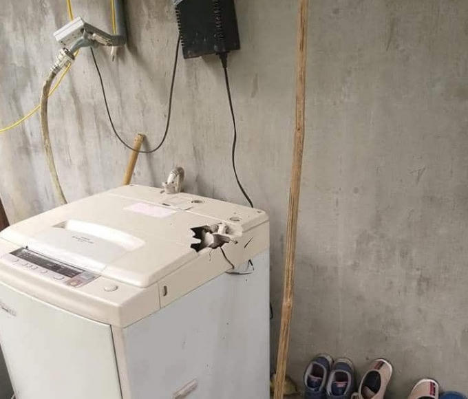 Một chiêc máy giặt bị hư hỏng do đá rơi trúng.