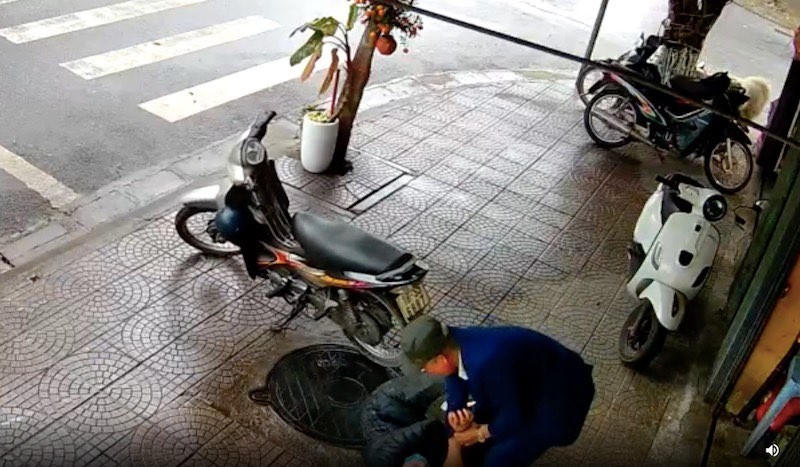 Anh Nghĩa (áo đen) bị đối tượng vật ngã xuống vỉa hè. (Ảnh: Cắt từ clip))