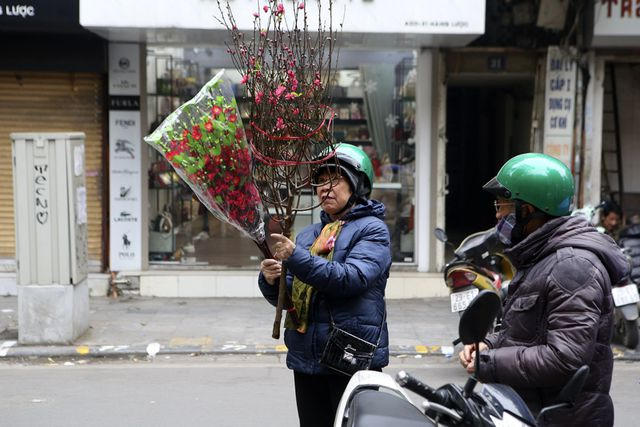 Những người già mua sắm đào Tết tại chợ hoa truyền thống.