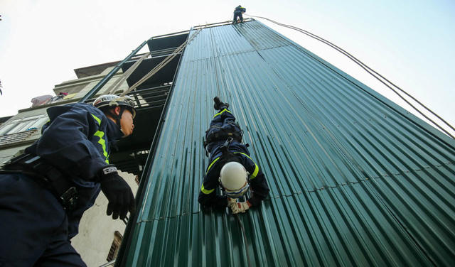 Đại uý Lan thực hiện diễn tập đu dây đầu hướng xuống đất từ độ cao tương đương toà nhà 5 tầng và tiếp đất an toàn.