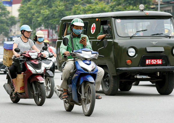 Lái xe ôm công nghệ Grab "dán mắt" vào điện thoại dù đang điều khiển xe trên đường đông (Chụp ngày 25/9 trên phố Liễu Giai, Hà Nội). - Ảnh: Khánh Linh