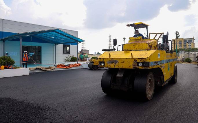 Khu vực bên ngoài, công nhân đang điều khiển xe lu cán mịn mặt đường. (Ảnh: Báo Người Lao động)