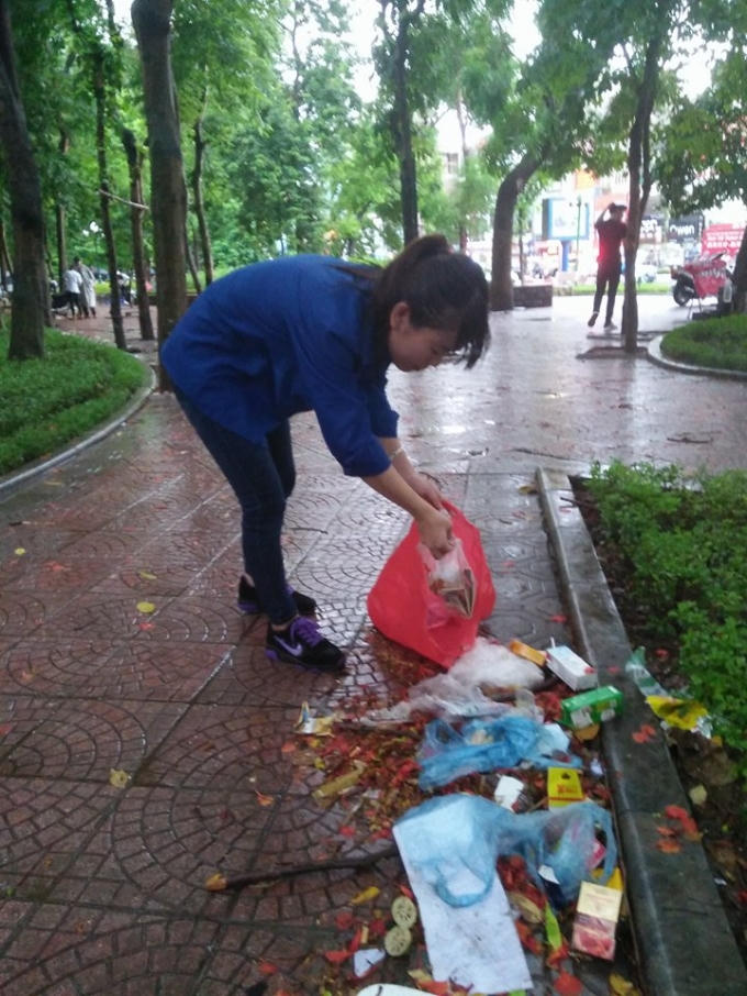 Thanh Hương, bạn tình nguyện viên tại điểm thi Đại Học Thủy Lợi giúp các cô lao công thu dọn rác sau ngày thi thứ 2. Ảnh: Trần Quang