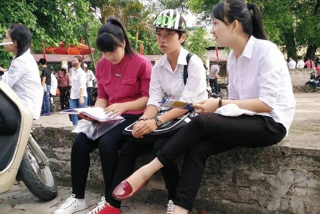 Thí sinh đến điểm thi sớm, tranh thủ ôn bài trước giờ thi môn đầu tiên (ảnh: Thái Bá).