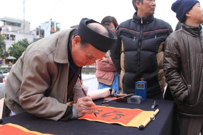 Ông đồ đang thể hiện những nét chữ mềm mại, trang nhã tại Hội chữ Xuân Bính Thân 2016.( Ảnh: Như Trường).