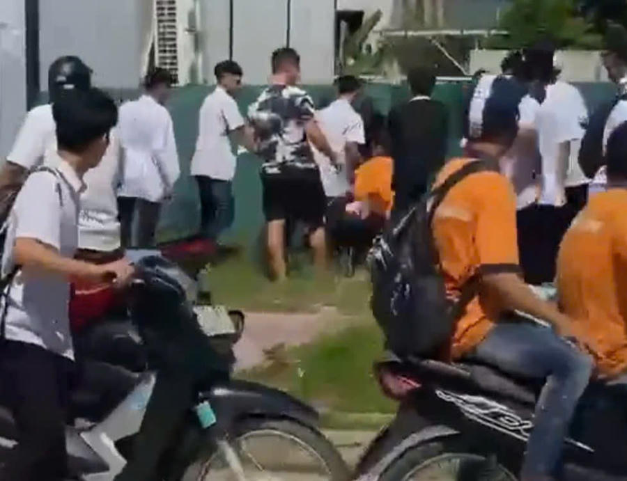 Khoảng hơn chục thanh niên, đa số mặc đồng phục trắng, vây quanh hành hung một học sinh. Ảnh: căt từ clip.
