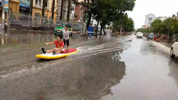 Một em nhỏ còn đứng trên ván trượt buông hai tay đùa giỡn.