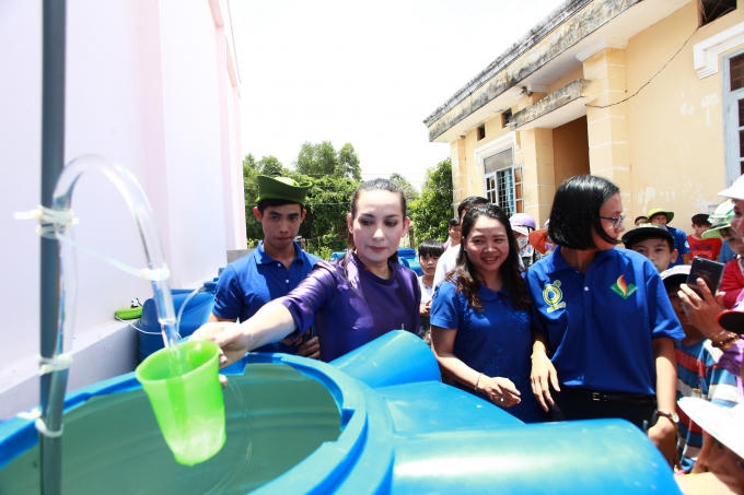 Phi Nhung hứng những giọt nước đầu tiên từ chiếc máy lọc nước.