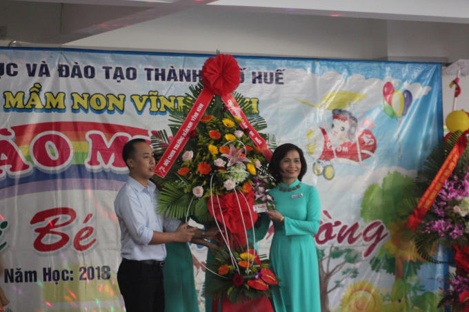 Cô Phan Thị Bạch Huệ đón nhận hoa chúc mừng từ đại diện hội phụ huynh .