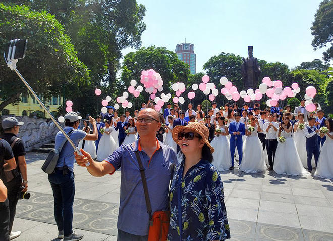 Nhiều vị khách ngoại quốc thích thú selfie trước cảnh 40 cặp đôi xúng xính váy áo.