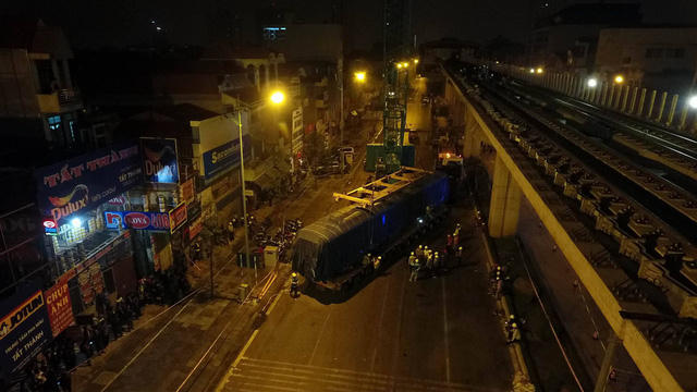 Công việc mắc cáp cẩu vào vào toa tàu gặp trục trặc, các công nhân đang làm lại. (Ảnh Dân trí)