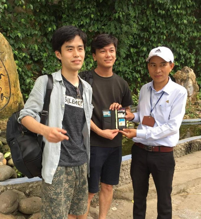 Đại diện BQL (phải) trao lại tài sản thất lạc cho du khách Lee Seung Hyeor (trái).