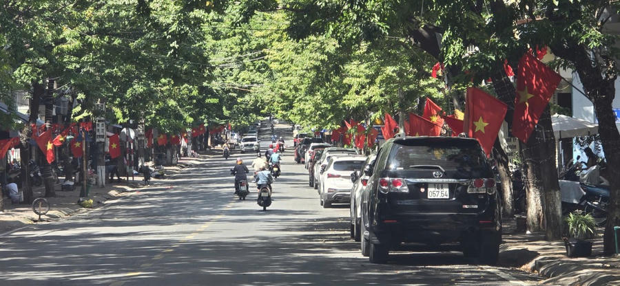Người dân lưu thông trên những con đường rợp bóng cây, hai bên rực rỡ sắc cờ, thể hiện tinh thần đoàn kết, đồng lòng.