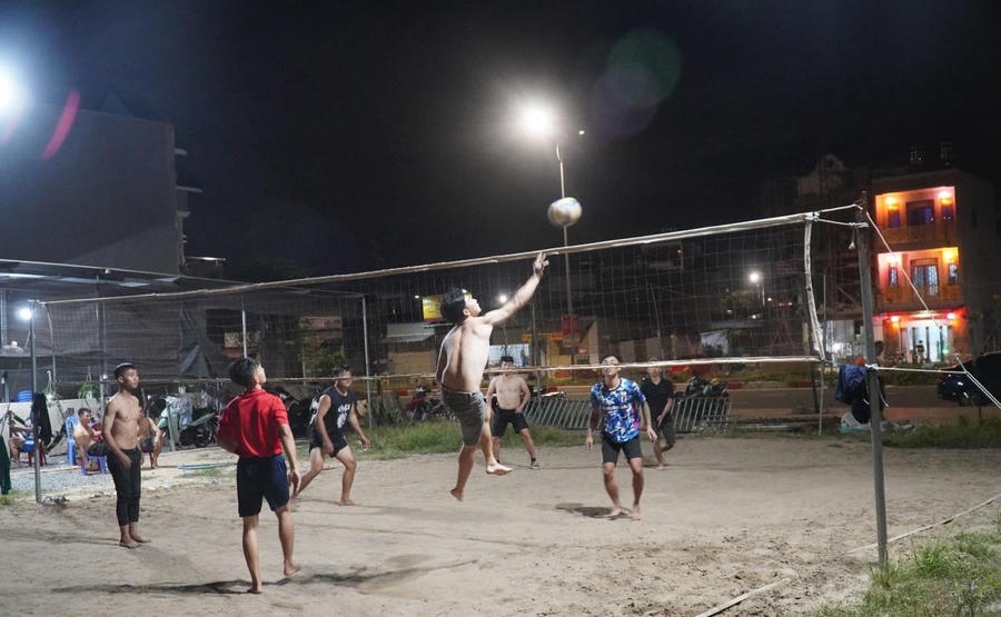 Thanh niên trong khu tái định cư đánh bóng chuyền tại một bãi đất trống.