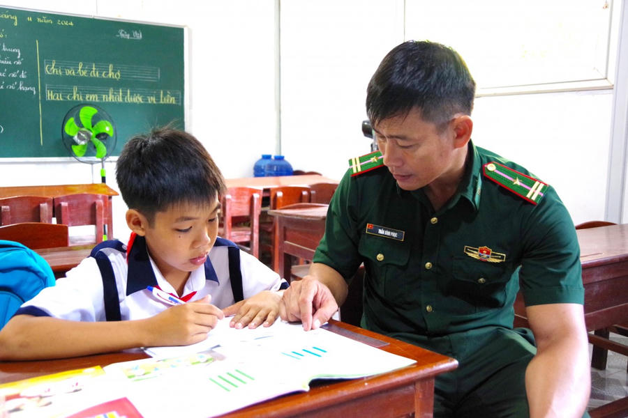 Các em học sinh trong “Lớp học tình thương” được thầy giáo quân hàm xanh tận tình hướng dẫn từng con chữ.