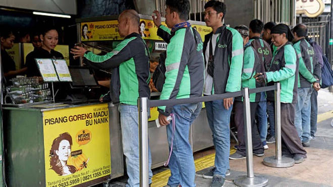 Các tài xế GrabFood đang xếp hàng để nhận đơn hàng trước một tiệm ăn ở Jakarta, Indonesia (Ảnh: Bloomberg).