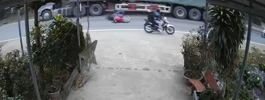 Người đàn ông đi xe máy màu đỏ ngã văng xuống đường và bị xe tải cán tử vong. (Ảnh cắt từ video).