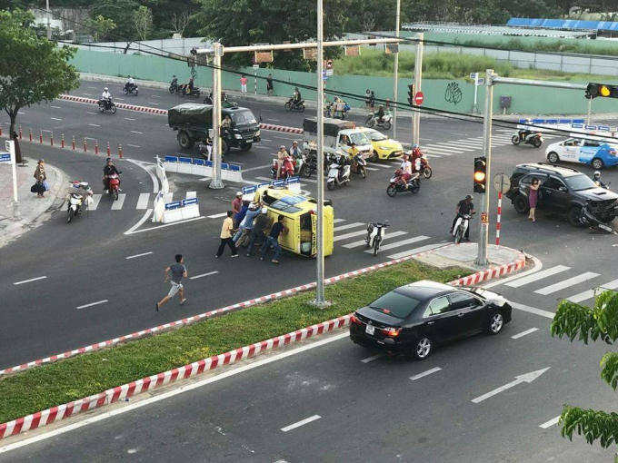 Người dân hợp lực đẩy chiếc xe taxi bị lật ngửa để giúp tài xế thoát ra ngoài. Ảnh: FB Bách Khoa.