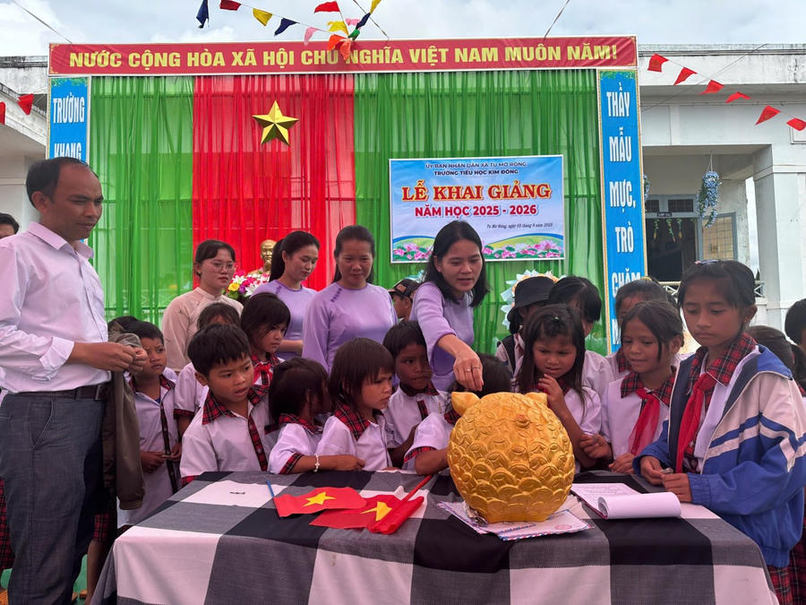 Các em học sinh cùng cô giáo bỏ tiền vào heo đất gây quỹ để nấu ăn trưa miễn phí và hỗ trợ học sinh nghèo, mồ côi.