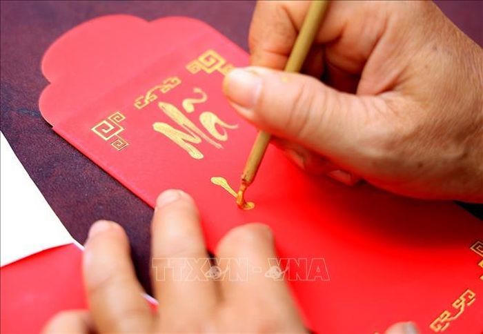 Ông đồ viết thư pháp Việt trên phong bao lì xì.