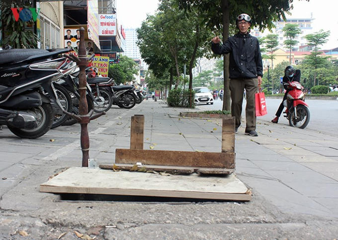 Cách đó chưa tới 100m, một hố ga lớn cũng bị mất nắp hàng năm nay được người dân dùng gỗ, gậy che chắn tạm bợ.