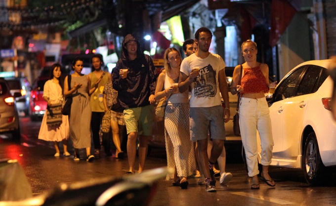 Nhóm du khách nước ngoài đội mưa đi chơi.