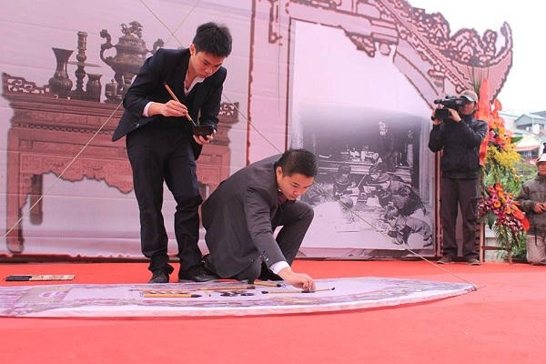 Nhà thư pháp trẻ tuổi nhất Hội chữ Xuân là Nguyễn Tô Tâm An (bên trái) sinh năm 1997 đang thể hiện tác phẩm của mình. ( Ảnh: Như Trường)